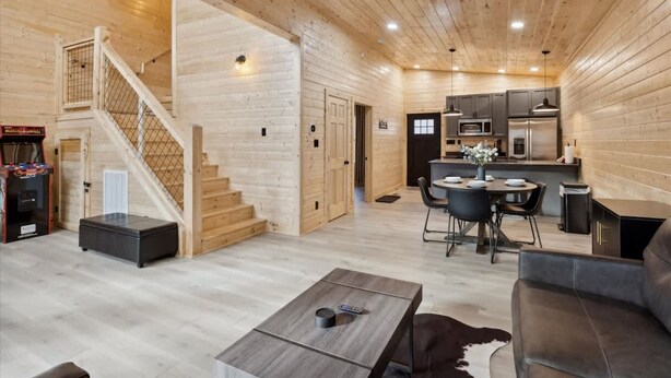 A wooden interior with a staircase, a dining area, and a kitchen. - Green Black Bear Cabins by Beyond Expectations (Sevierville)