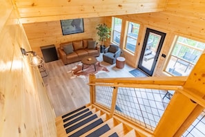 Un intérieur en bois comprenant un canapé, des fauteuils, une table basse et un escalier.