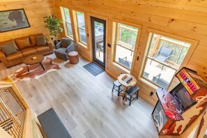 A wooden cabin interior with a sofa, armchair, and a table with a chessboard. - Green Black Bear Cabins by Beyond Expectations (Sevierville)