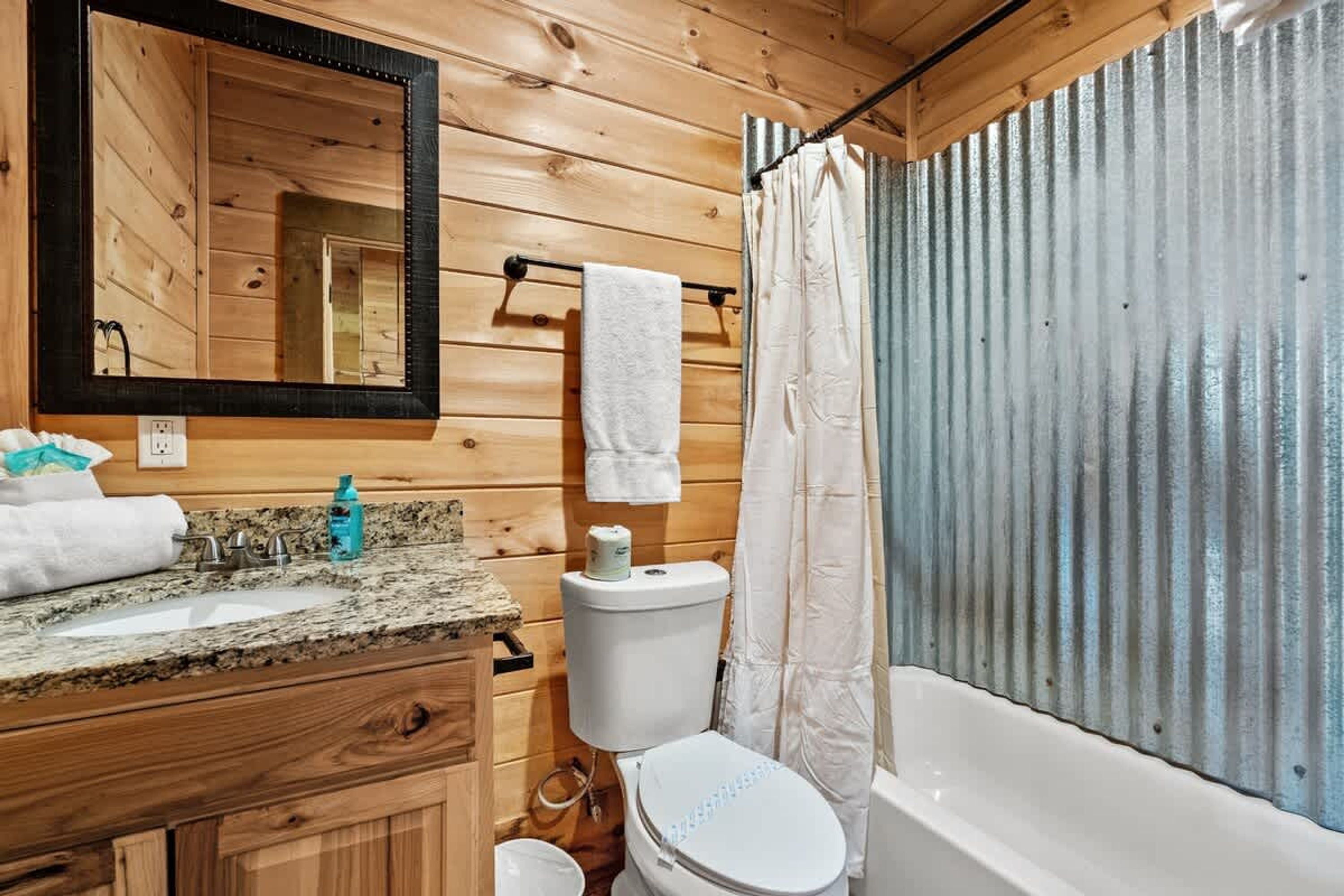 A wooden cabin bathroom with a sink, toilet, and bathtub.