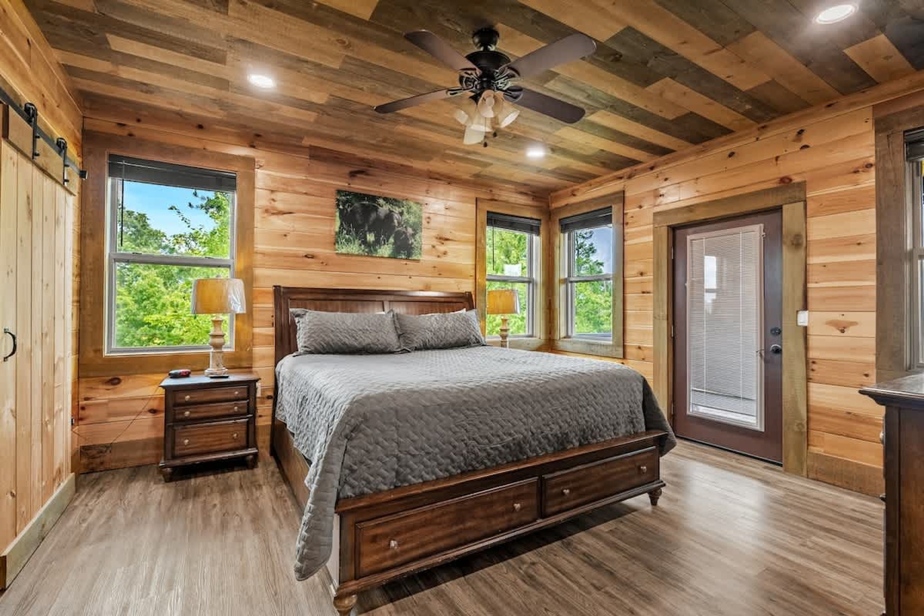 Ein Schlafzimmer einer Holzhütte mit einem Bett, Nachttischen und einem Deckenventilator.