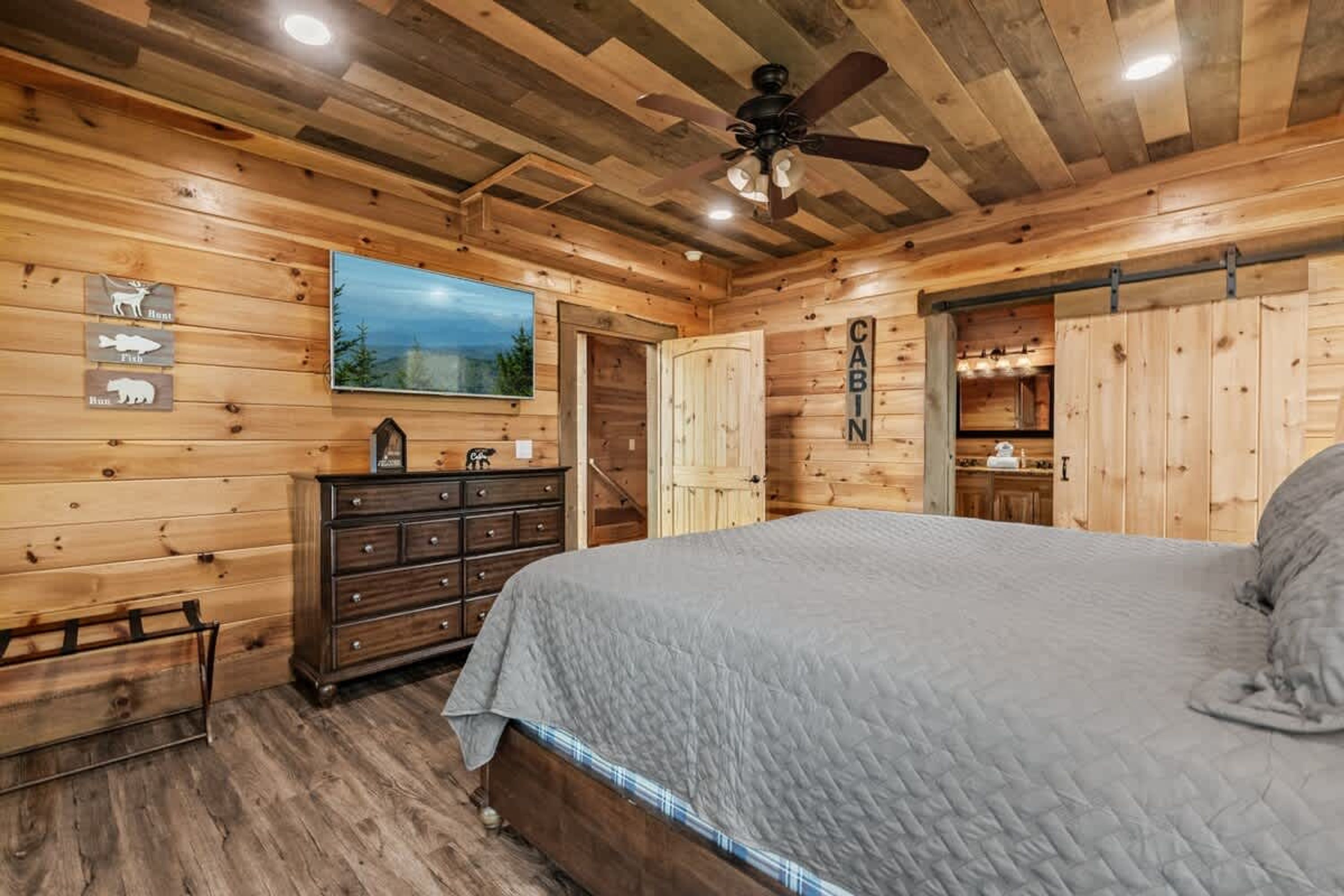 Ein schlicht eingerichtetes Schlafzimmer im Chalet-Stil mit einem Bett, einem Schminktisch und einem Deckenventilator.