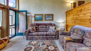 Un salon chaleureux avec un canapé, un tapis à motifs et deux tableaux encadrés accrochés au mur.