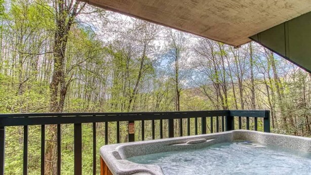 Un bain à remous sur une terrasse en bois, avec vue sur une zone boisée.