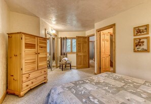 Un dormitorio con cama, armario de madera y una silla.