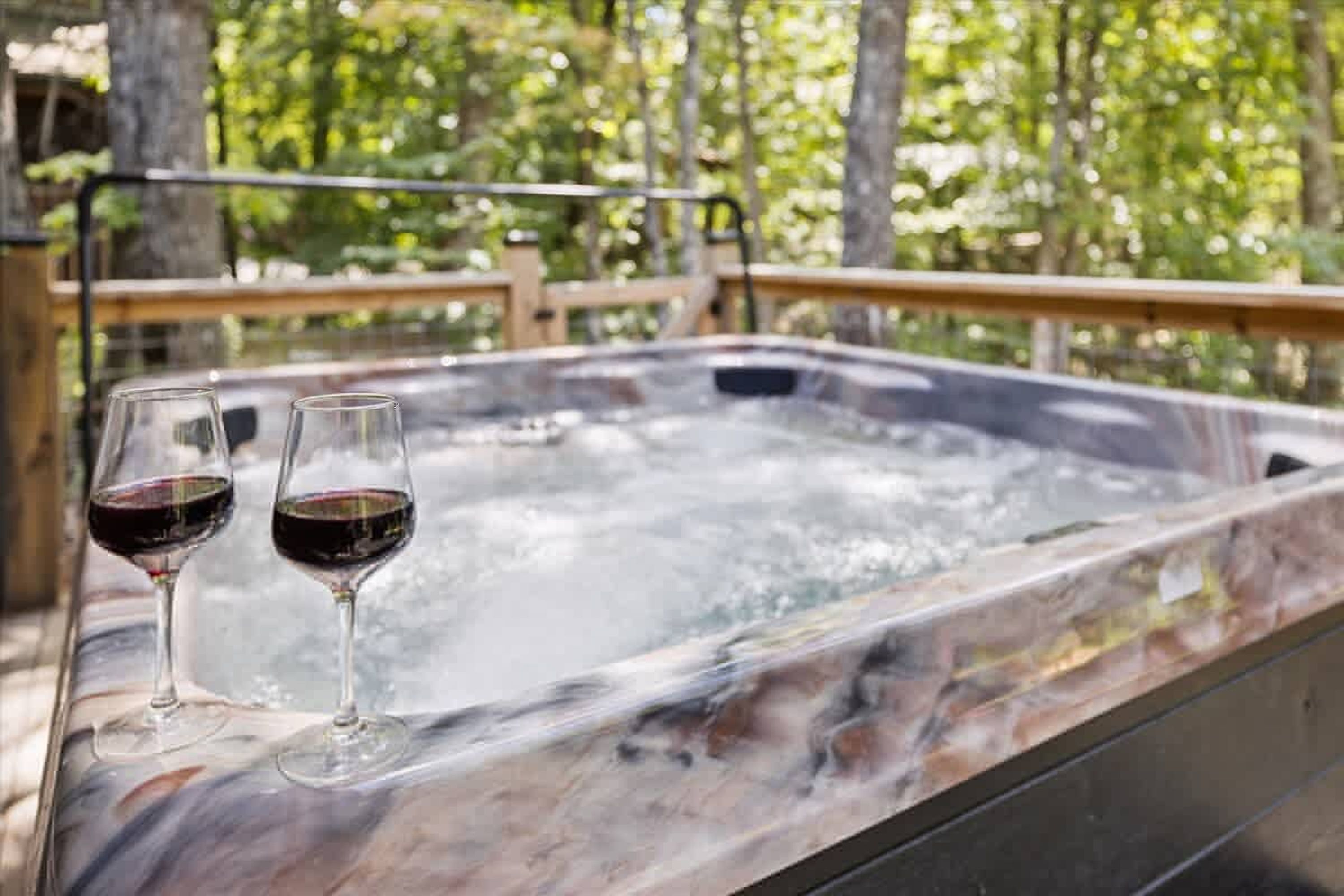 Ein Whirlpool mit zwei Gläsern Rotwein.