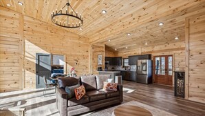A spacious log cabin interior with a living area, kitchen, and dining space. - Bearodise by Beyond Expectations With Hot Tub (Sevierville)