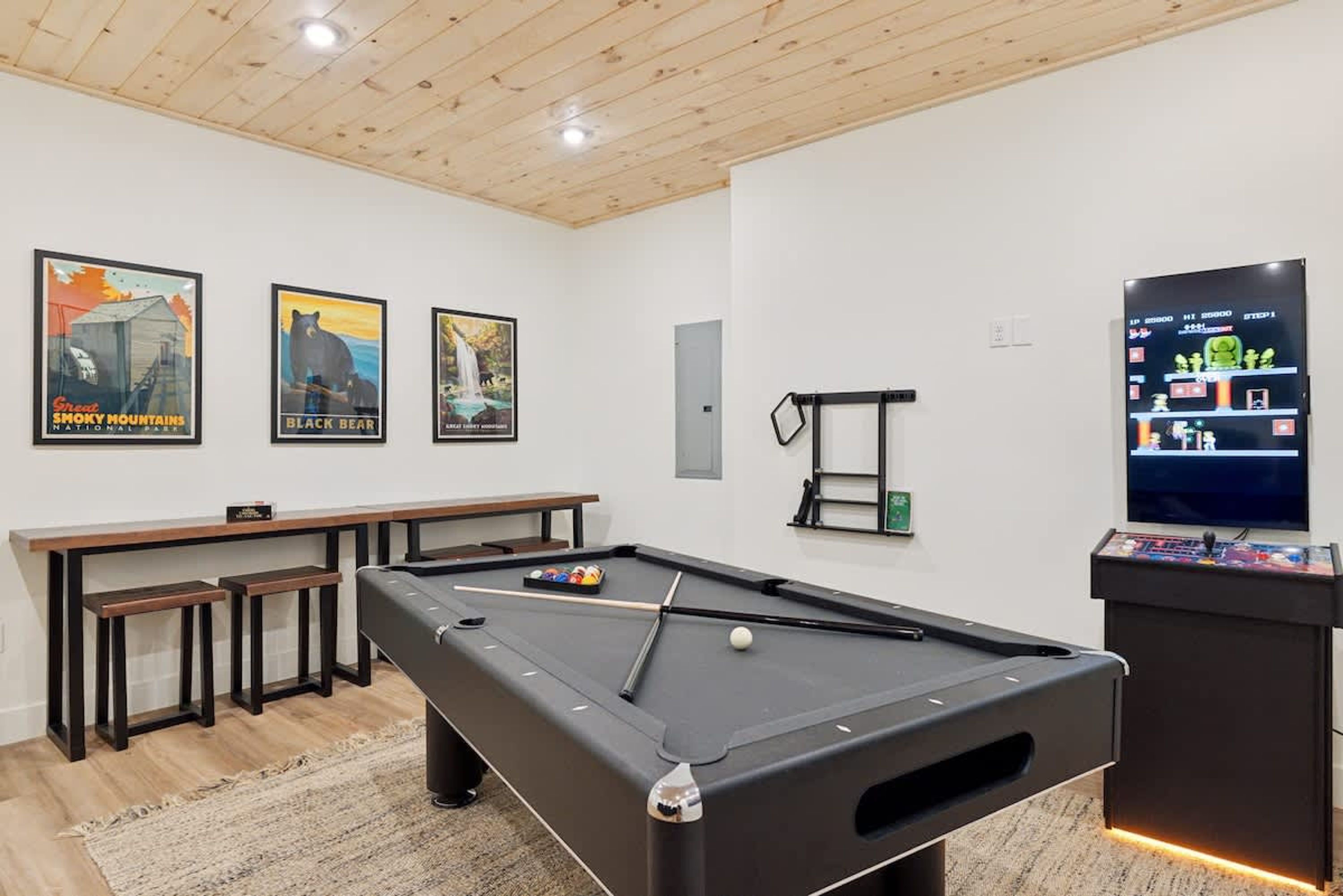 A pool table with a cue stick, a billiards ball, and a video game console.