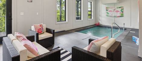 Zona junto a la piscina con mobiliario de mimbre y una piscina.