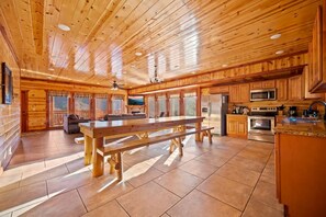 A spacious kitchen with wooden cabinets, a large dining table, and modern appliances. - Paradise Pointe Pool Lodge by Beyond Expectations (Sevierville)