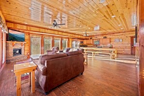 A spacious living room with a brown leather sofa, wooden flooring, and a fireplace. - Paradise Pointe Pool Lodge by Beyond Expectations (Sevierville)