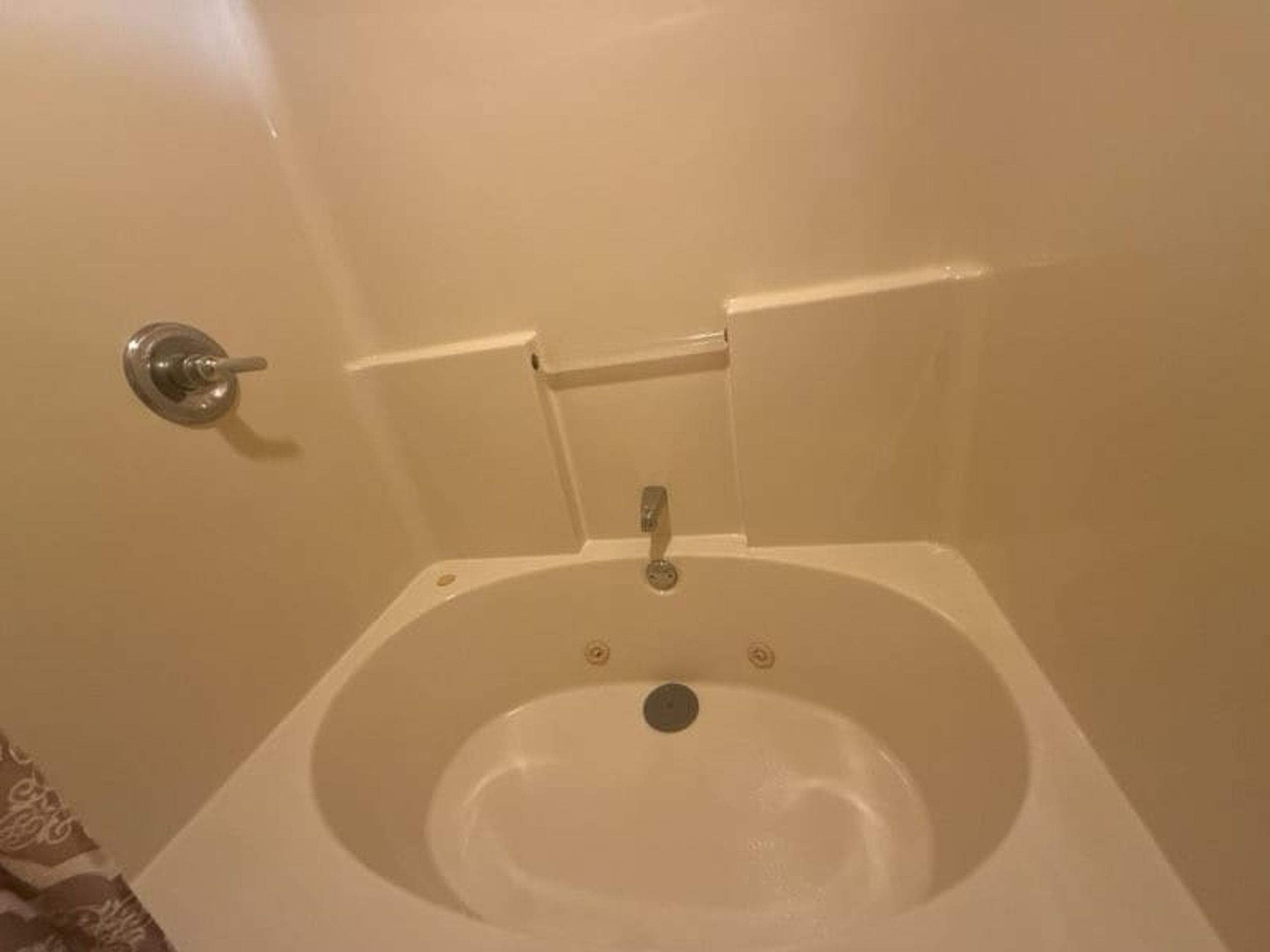 A small, white, freestanding bathtub with a faucet and a drain.