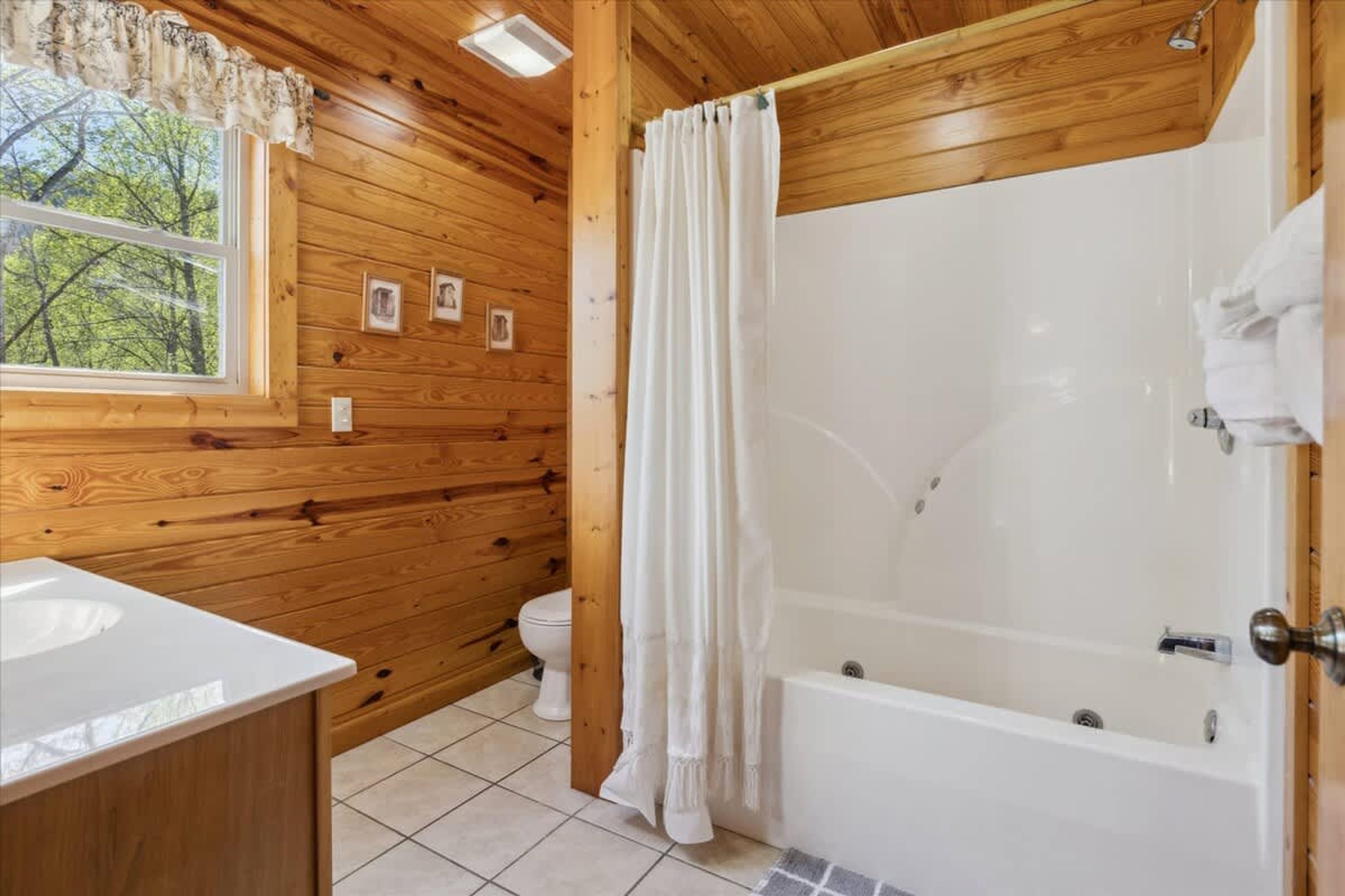 A wooden cabin bathroom with a bathtub, toilet, and sink.