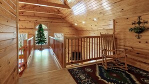 Ein Holzinnenraum mit Treppe, Weihnachtsbaum und Teppich mit Muster.