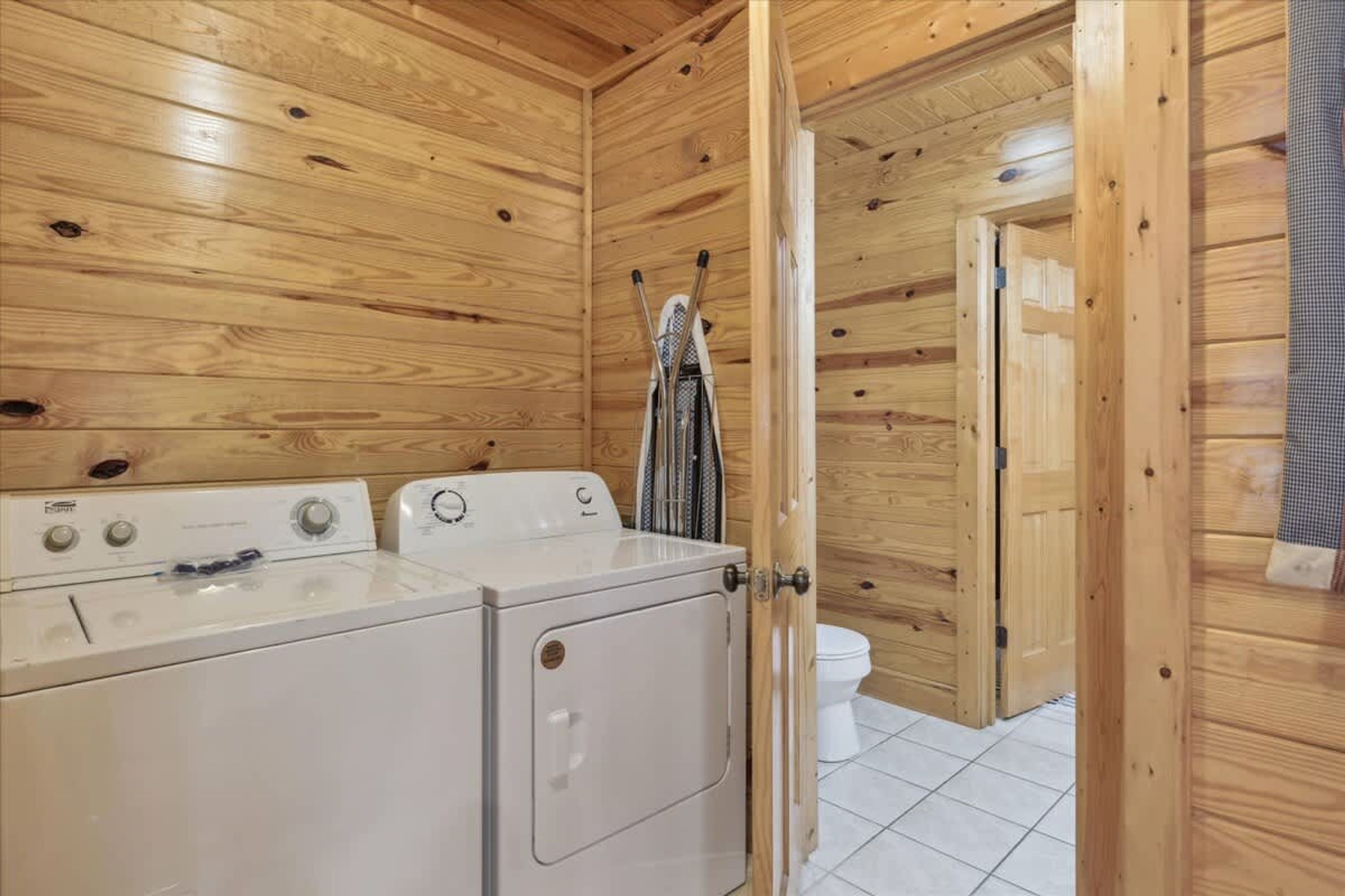 Una lavanderia con due lavatrici, un'asciugatrice e una porta in legno che dà su un'altra stanza.