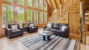 Un salon spacieux doté d’une grande fenêtre, d’un escalier et d’un décor intérieur en bois.
