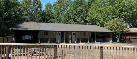 A single-story building with a covered porch and a fenced parking area.