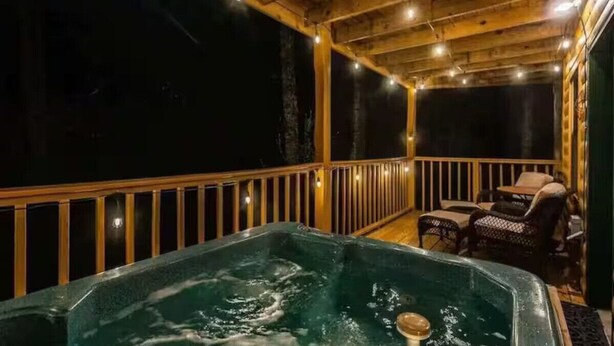 A hot tub with a wooden deck and outdoor furniture. - A Little Bit of Country by Beyond Expectations (Pigeon Forge)