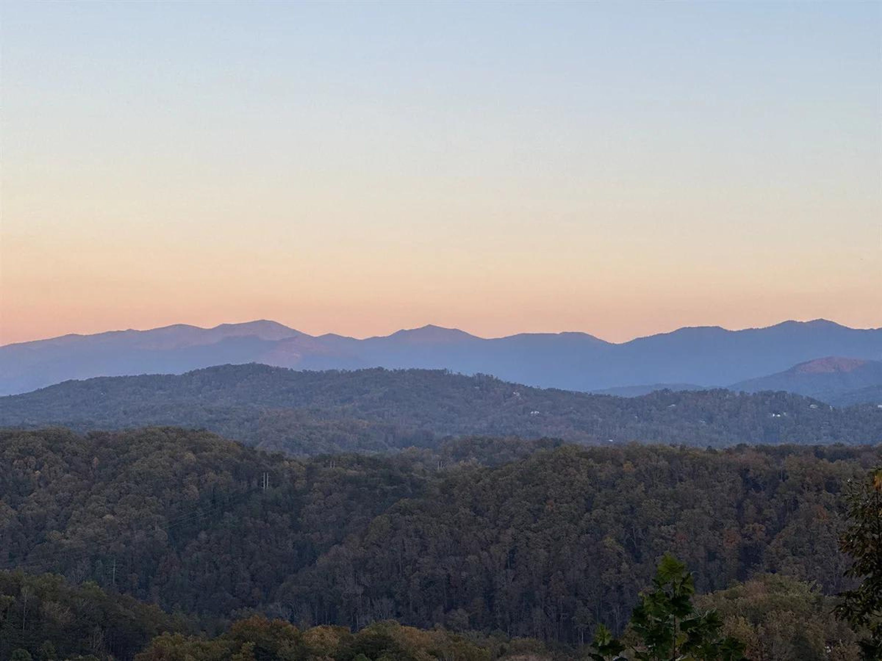 Un paysage montagneux, avec de vastes forêts et des chaînes de montagnes qui s’étendent à l’horizon.