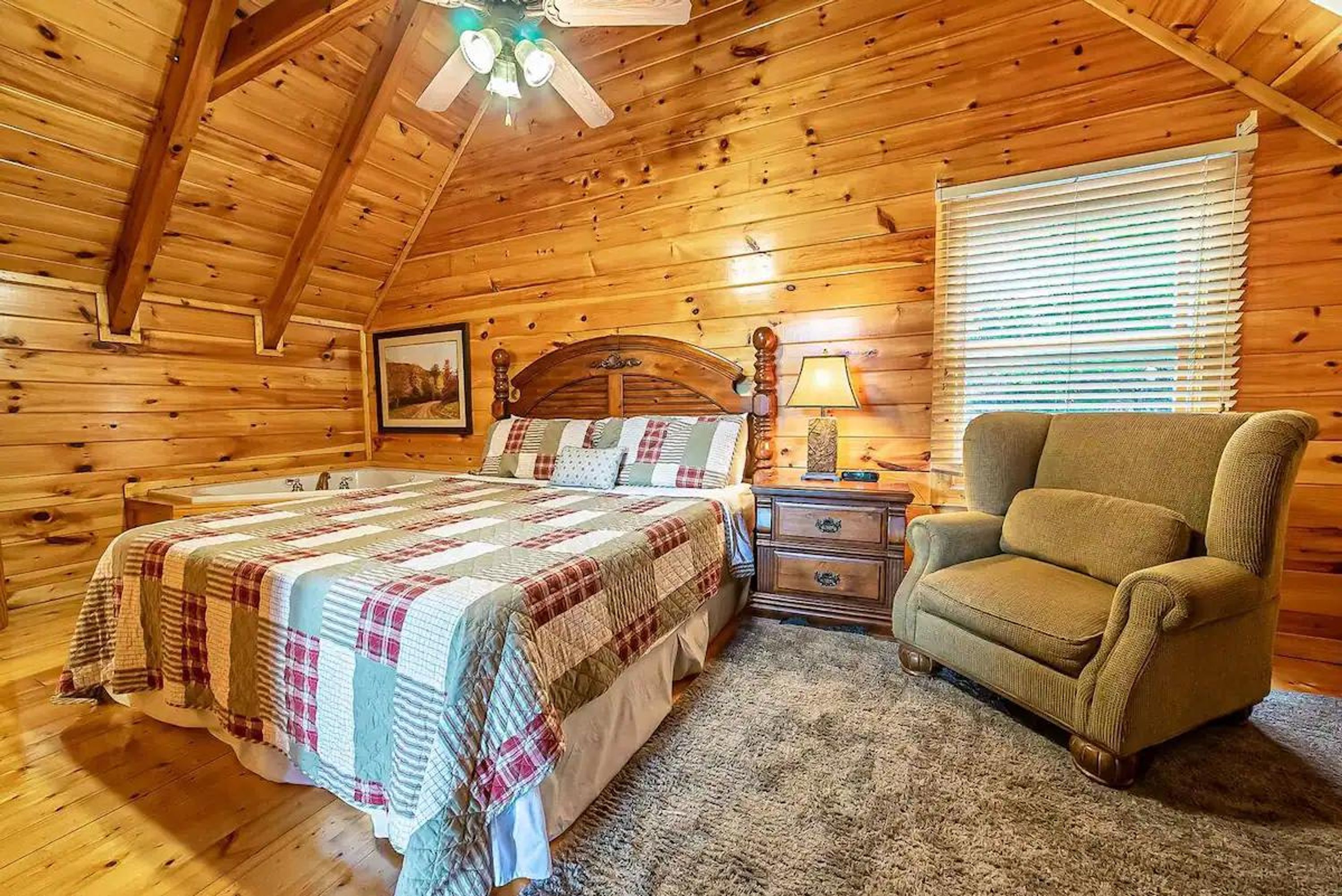 A log cabin bedroom with a bed, a chair, a nightstand, and a ceiling fan.