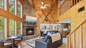 A spacious living area with a fireplace, a dining table, and a sofa. - Hideaway at the River by Beyond Expectations (Sevierville)