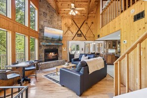 A spacious living area with a fireplace, a dining table, and a sofa. - Hideaway at the River by Beyond Expectations (Sevierville)