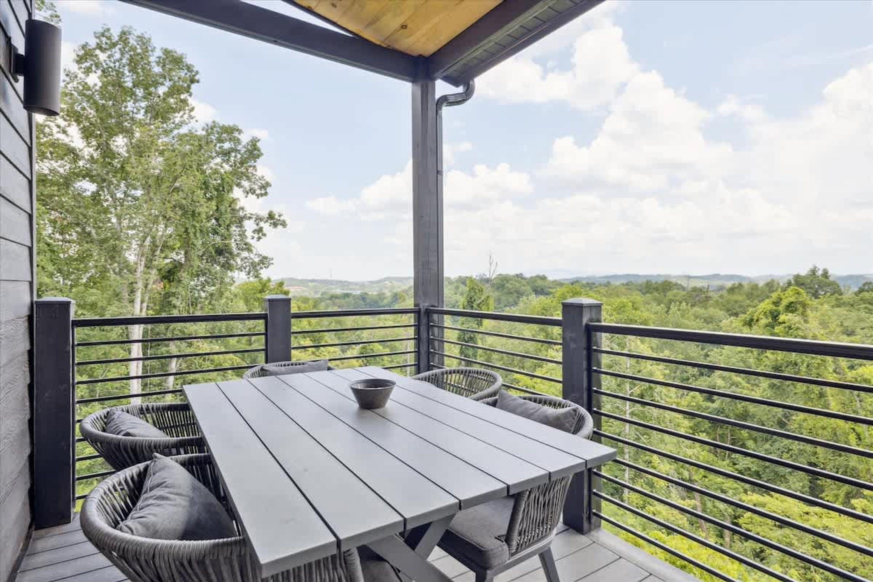 Un espace extérieur aménagé, abrité et doté d’une table et de chaises, offrant une vue sur un paysage verdoyant et luxuriant.