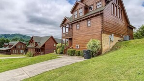 Ein großes Holzhaus mit Balkon, überdachter Veranda und kleinem Vorgarten.
