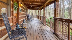 A wooden cabin with a porch, rocking chairs, and a bench. - Laceys Place by Beyond Expectations With Hot Tub (Sevierville)