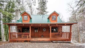 A cabin with a front porch, two chimneys, and a green roof. - Cabin Fever by Beyond Expectations With Hot Tub (Gatlinburg)