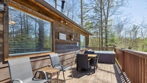 Une terrasse en bois avec des meubles d’extérieur, une pancarte indiquant « Bienvenue à la terrasse », et une vue sur les arbres.
