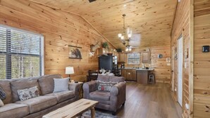 L'intérieur d'une cabine est aménagé avec des éléments en bois, un canapé, un fauteuil, une table à manger et un coin cuisine.