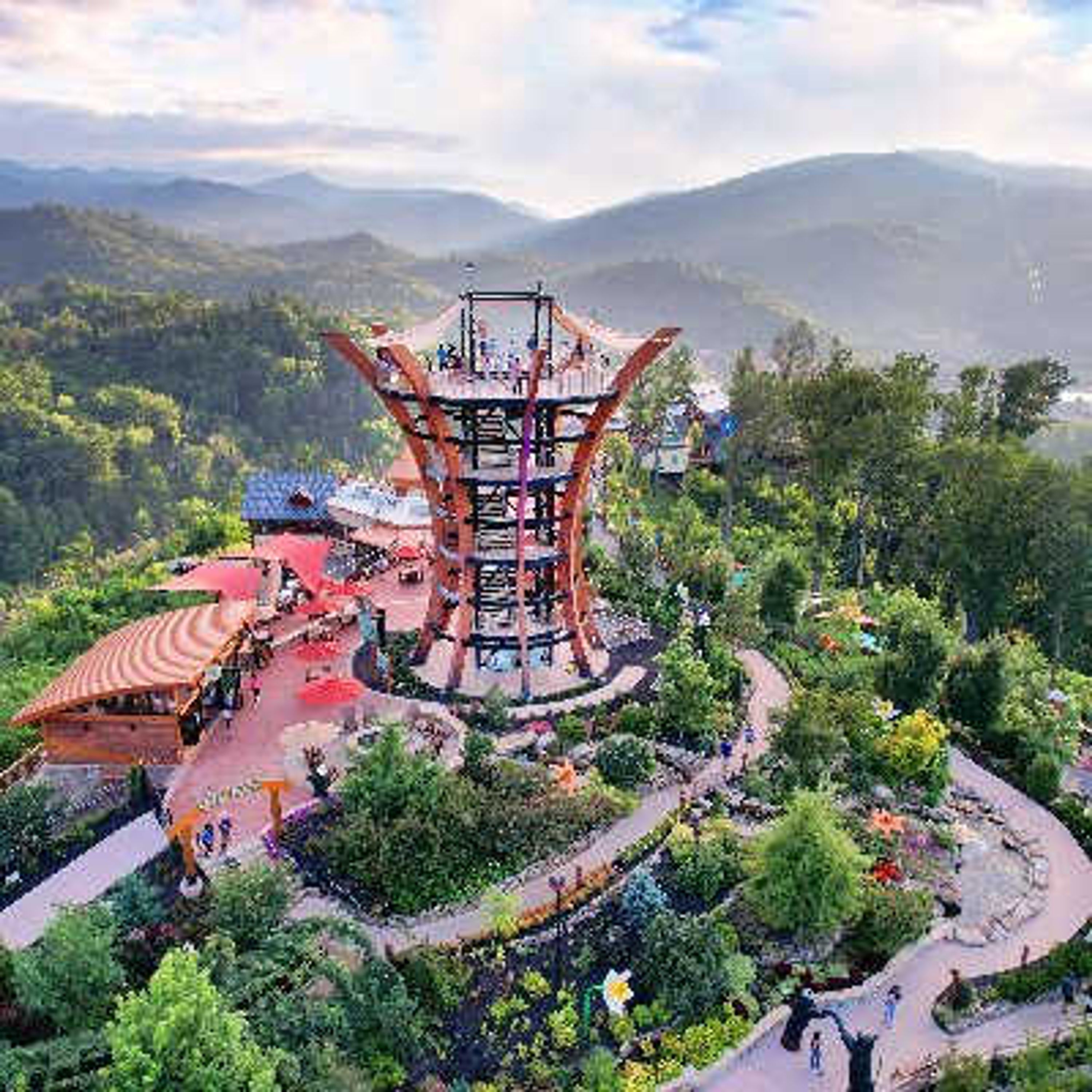 A large, multi-level structure with a central tower, surrounded by lush greenery and a winding path.