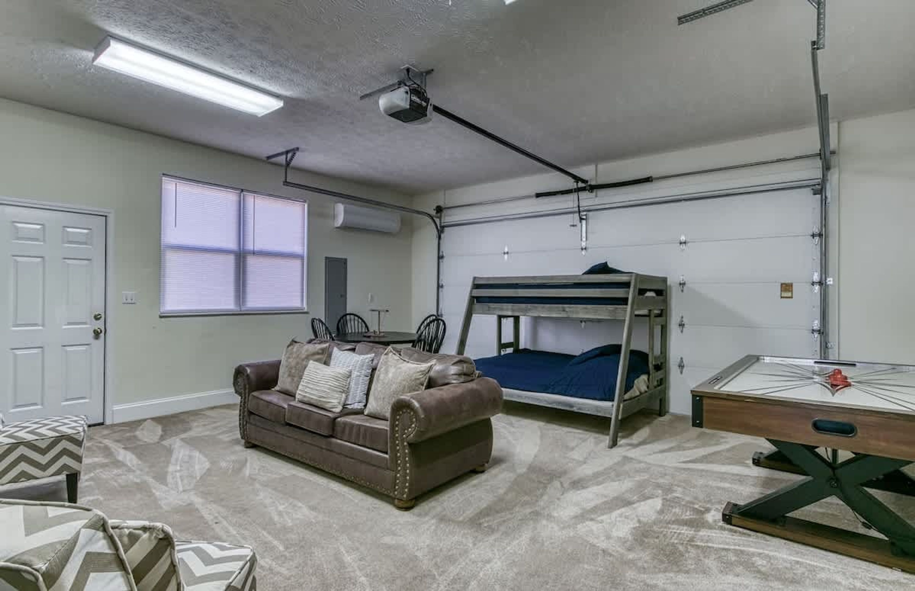 A room with a bunk bed, a sofa, a table, and a projector.