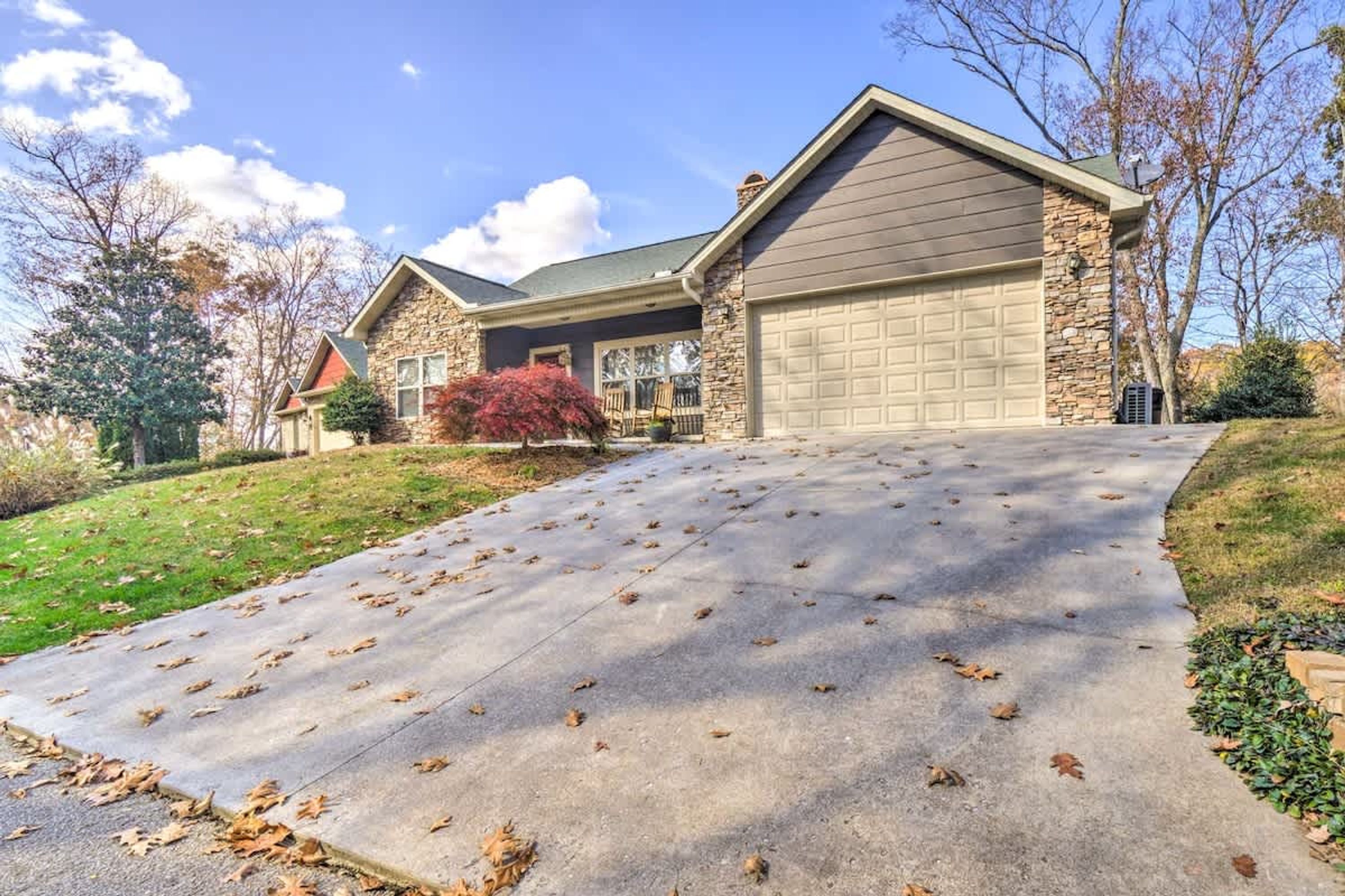 A residential house with a garage, a driveway, and a stone facade.