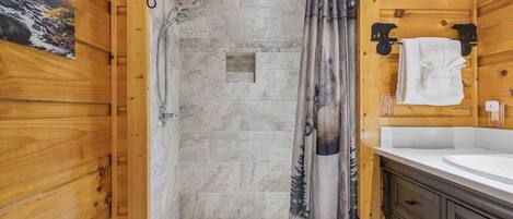 A wooden interior with a shower, a sink, and a towel rack.