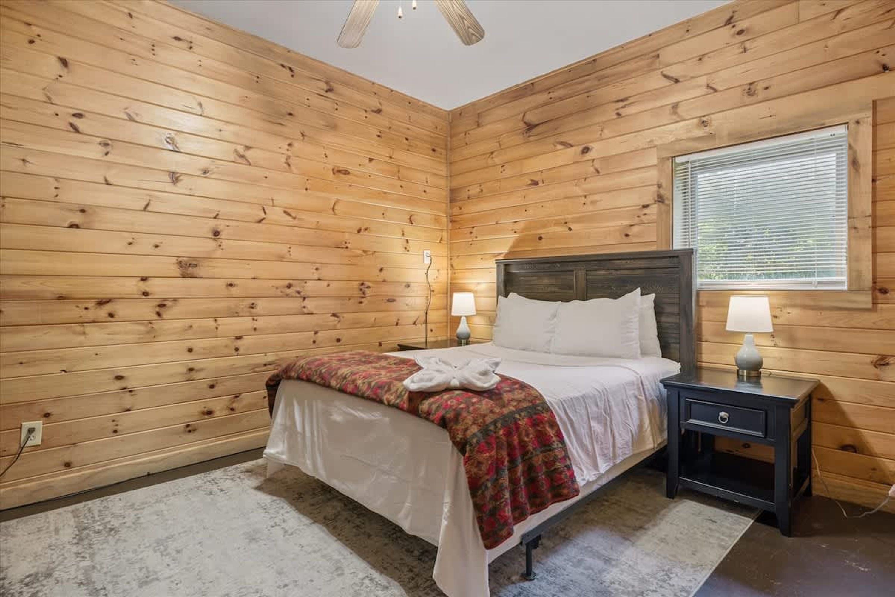 Una stanza con rivestimenti in legno, un letto, due lampade sui comodini e una finestra.