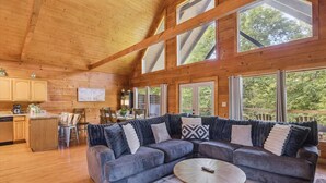Ein Holzblockbau-Innenraum mit einer großen, L-förmigen Couch, einem Essbereich und großen Fenstern.