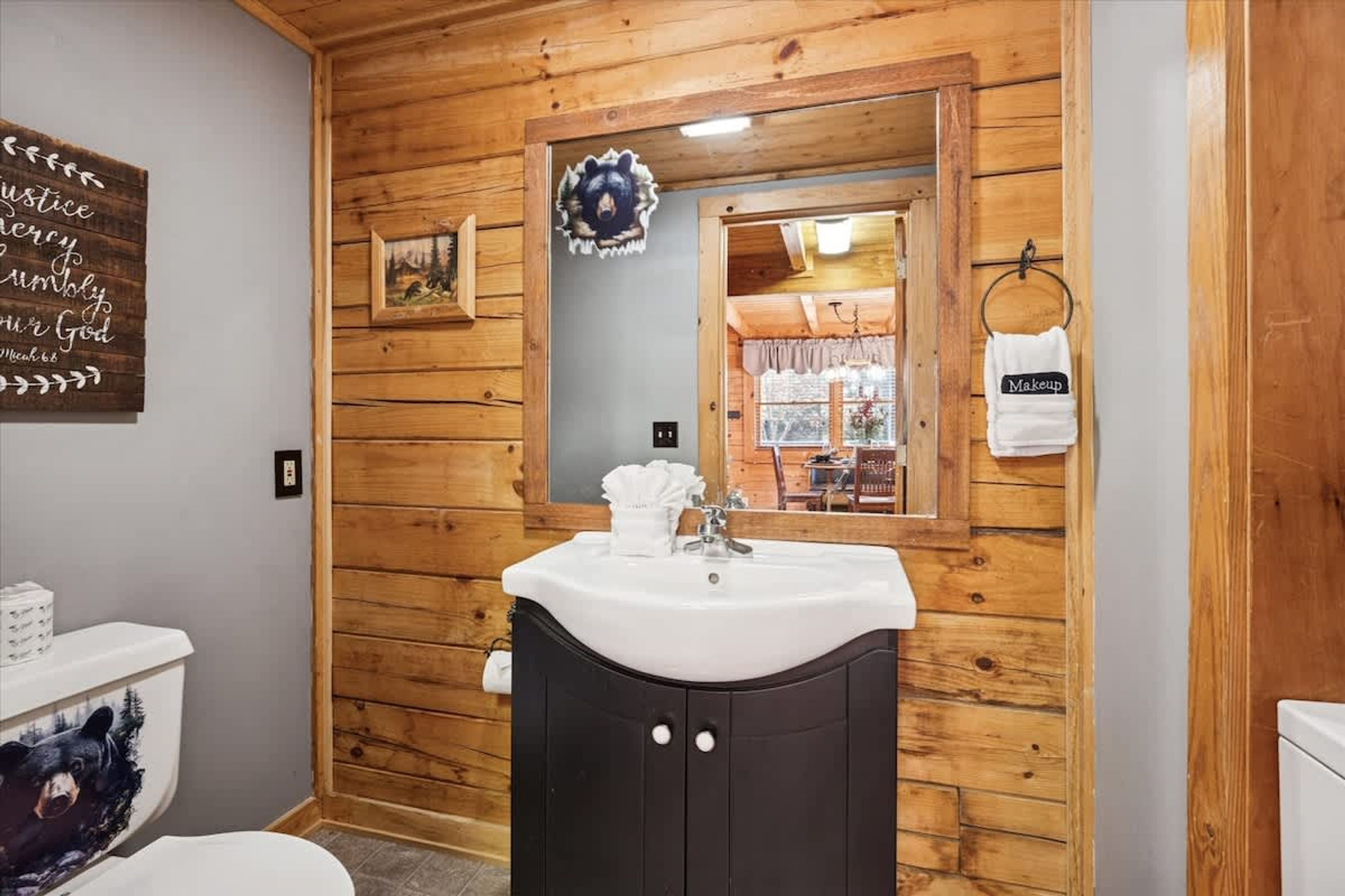 Un baño con paredes de madera, un lavabo, un espejo y un perchero para toallas.