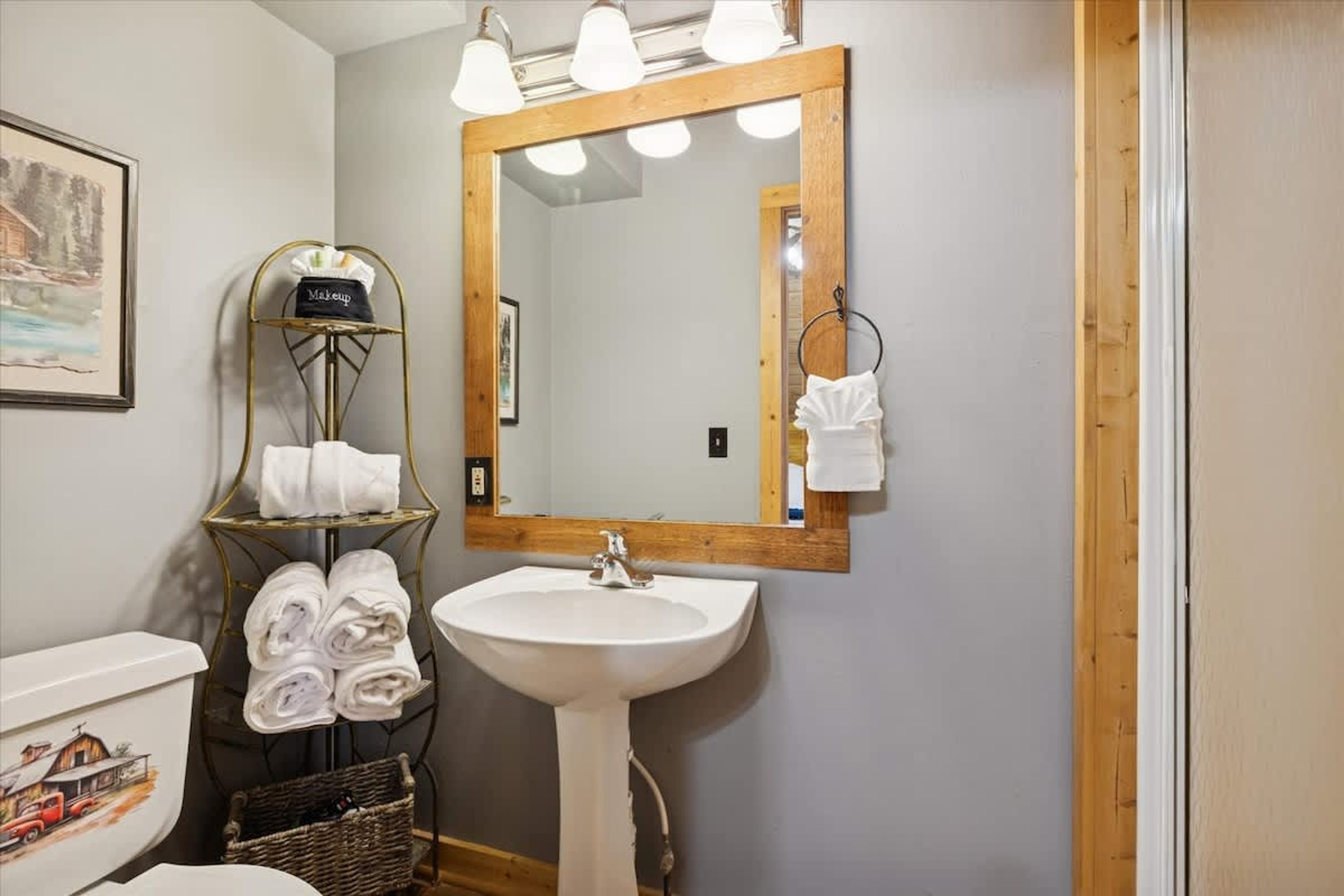 A bathroom with a sink, mirror, towel rack, and a framed picture on the wall.
