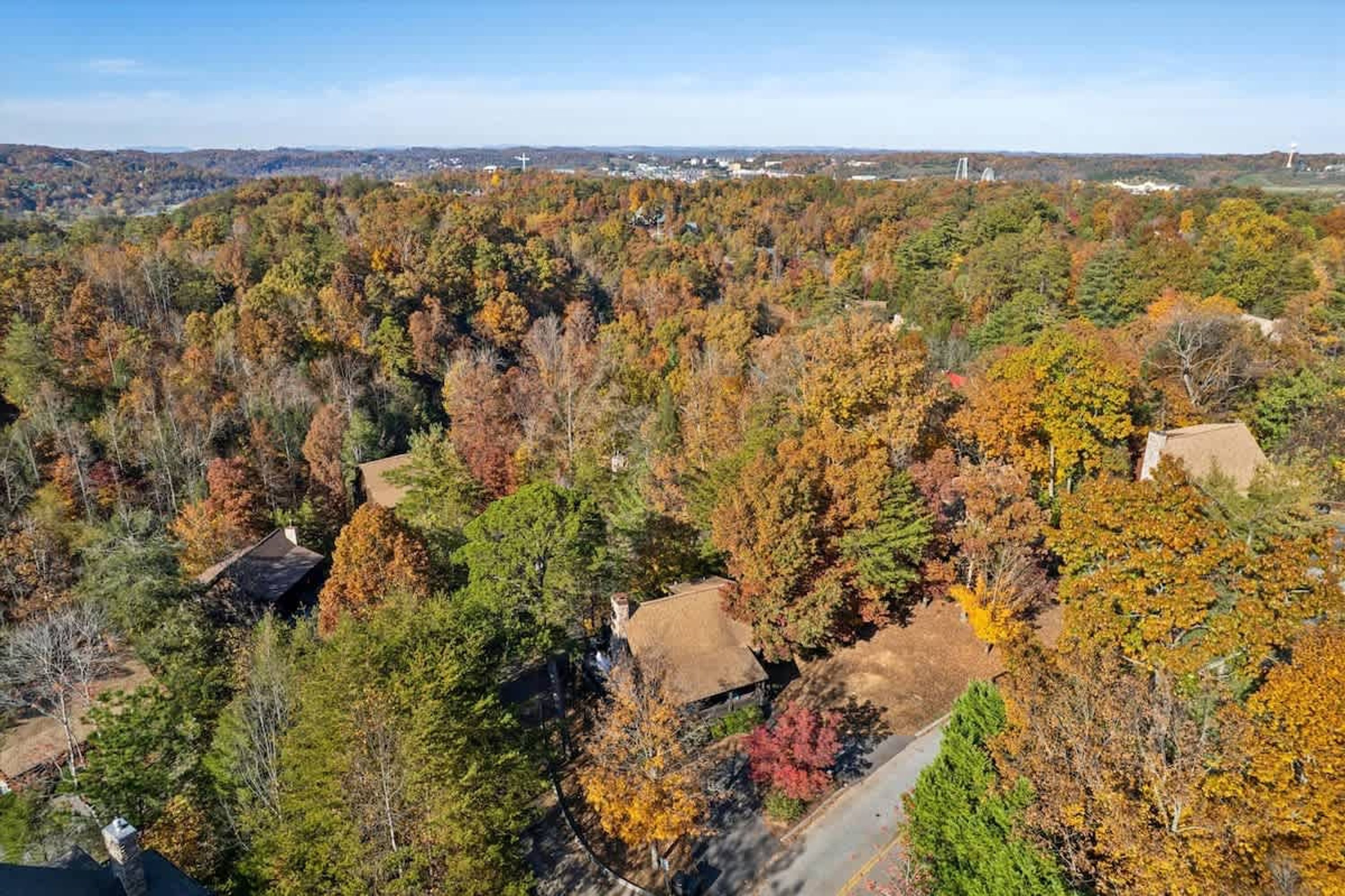 A residential area with houses surrounded by dense autumn foliage.