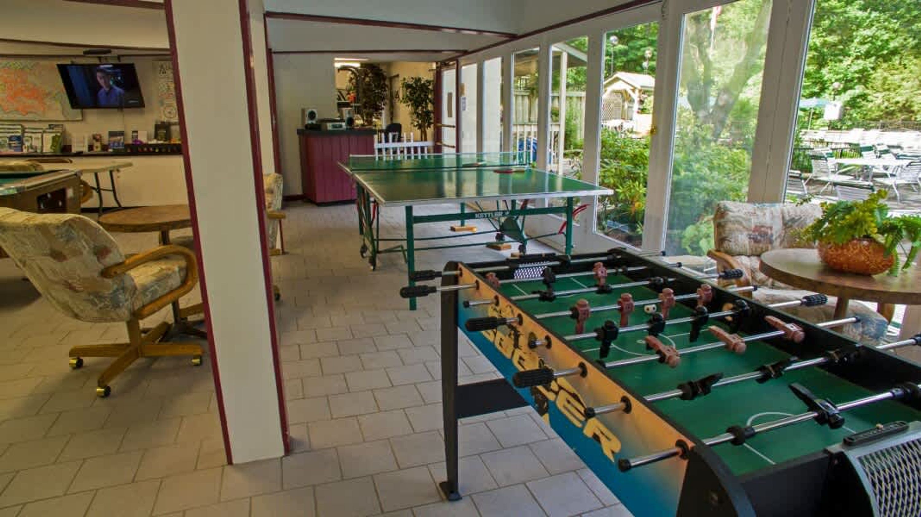 Ein Zimmer mit Kicker, Fernseher und Blick ins Freie.