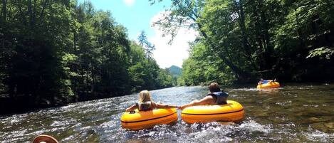 People floating on yellow tubes in a river surrounded by trees.