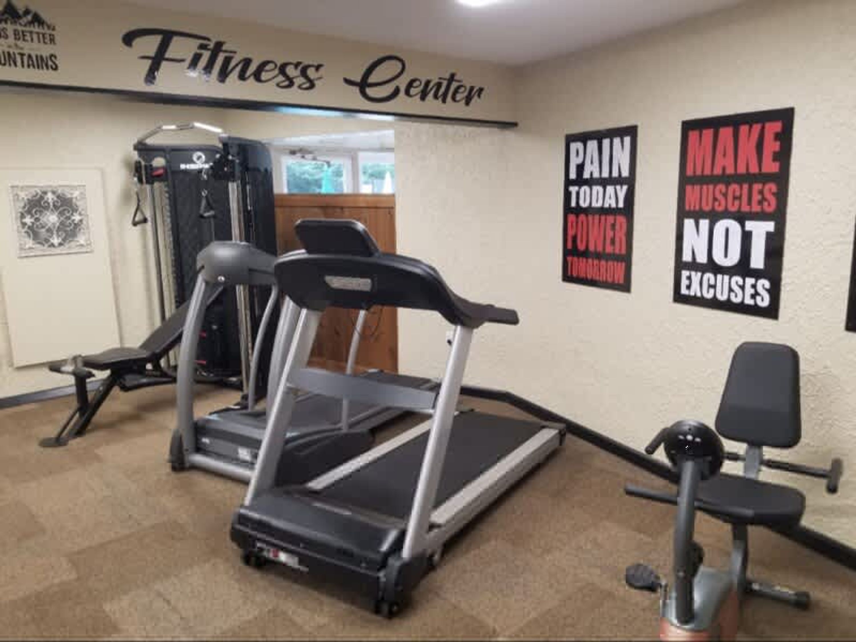 A fitness center with treadmills, a weight bench, and motivational posters on the walls.