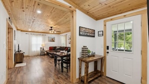 Un salón con suelo de madera, un sofá, una mesa de comedor y una puerta con ventanal.