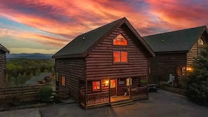 A log cabin with a porch, a visible sign, and a mountain backdrop. - Majestic Overlook II by Beyond Expectations (Sevierville)