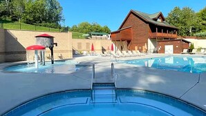 A swimming pool with a ladder, lounge chairs, and a wooden building in the background. - Majestic Overlook II by Beyond Expectations (Sevierville)