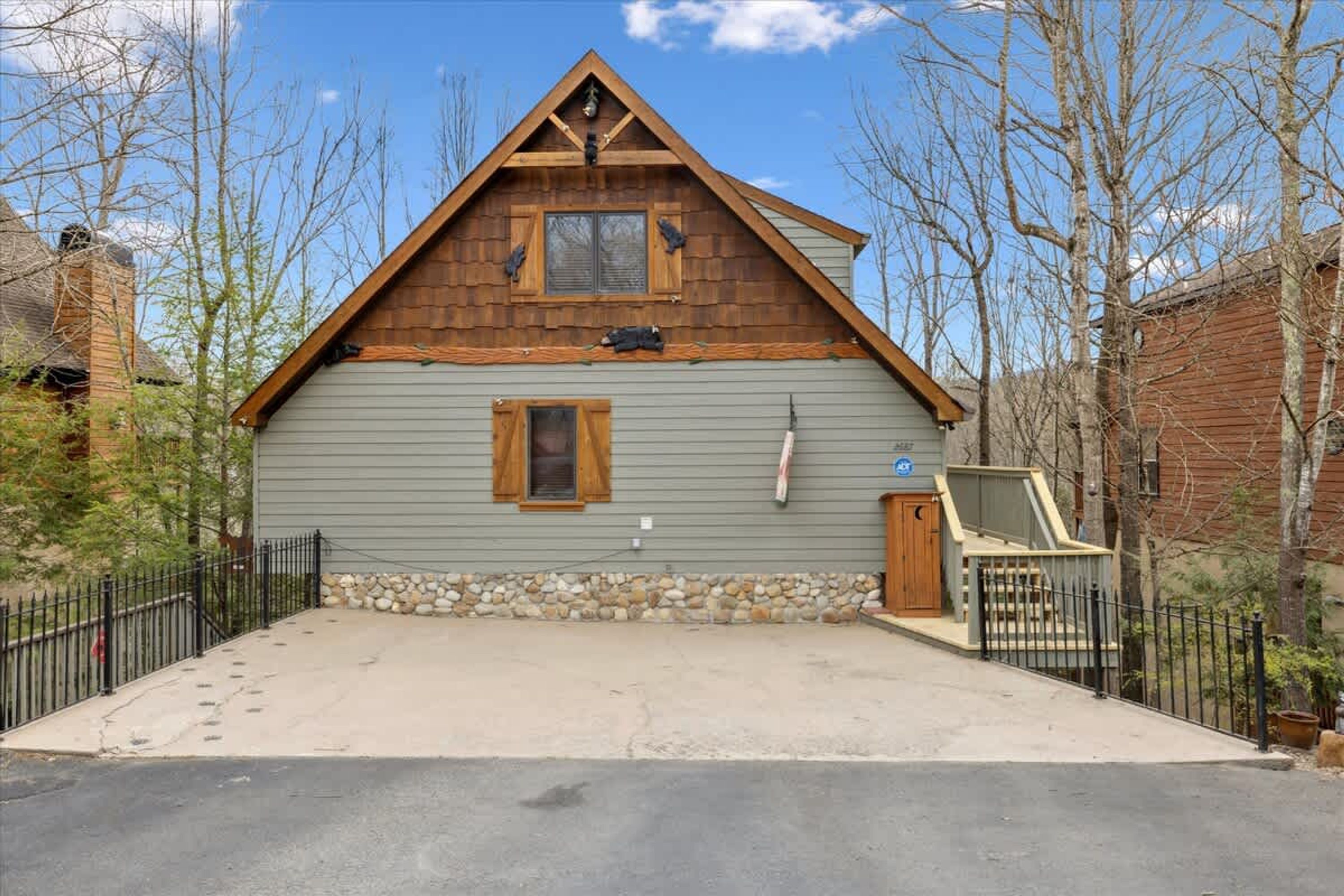 A two-story cabin with a stone foundation, wooden siding, and a gabled roof.