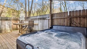 Un bain à remous avec une terrasse en bois, une table et des chaises.