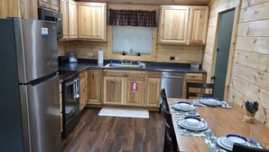 Une cuisine compacte avec des meubles en bois, un réfrigérateur en acier inoxydable, un lave-vaisselle et une table à manger pour quatre personnes.